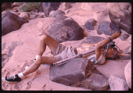 Photographer Tad Nichols on his back in Glen Canyon sand