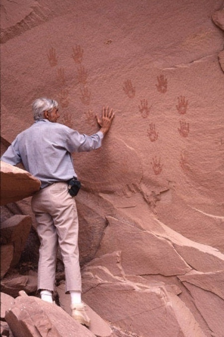 Tad Nichols compares his hand with prints on a cliff wall