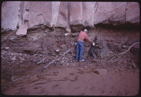 Tad Nichols collects water from a cliffside spring